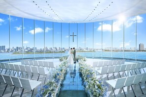 A modern venue with a glass floor, seating arranged in rows, and a city skyline view. - Hilton Tokyo Odaiba (Tokyo)