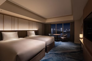 Une chambre d’hôtel avec deux lits, une vue sur la ville, une petite table et une chaise.
