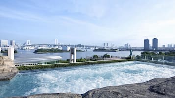 A rooftop infinity pool with a view of a city skyline and a bridge.