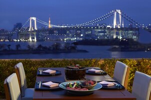Mesa posta para jantar com vista para uma ponte e paisagem urbana.