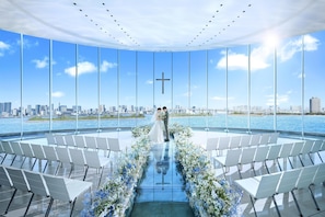 A modern venue with a glass floor, seating arranged in rows, and a city skyline view.