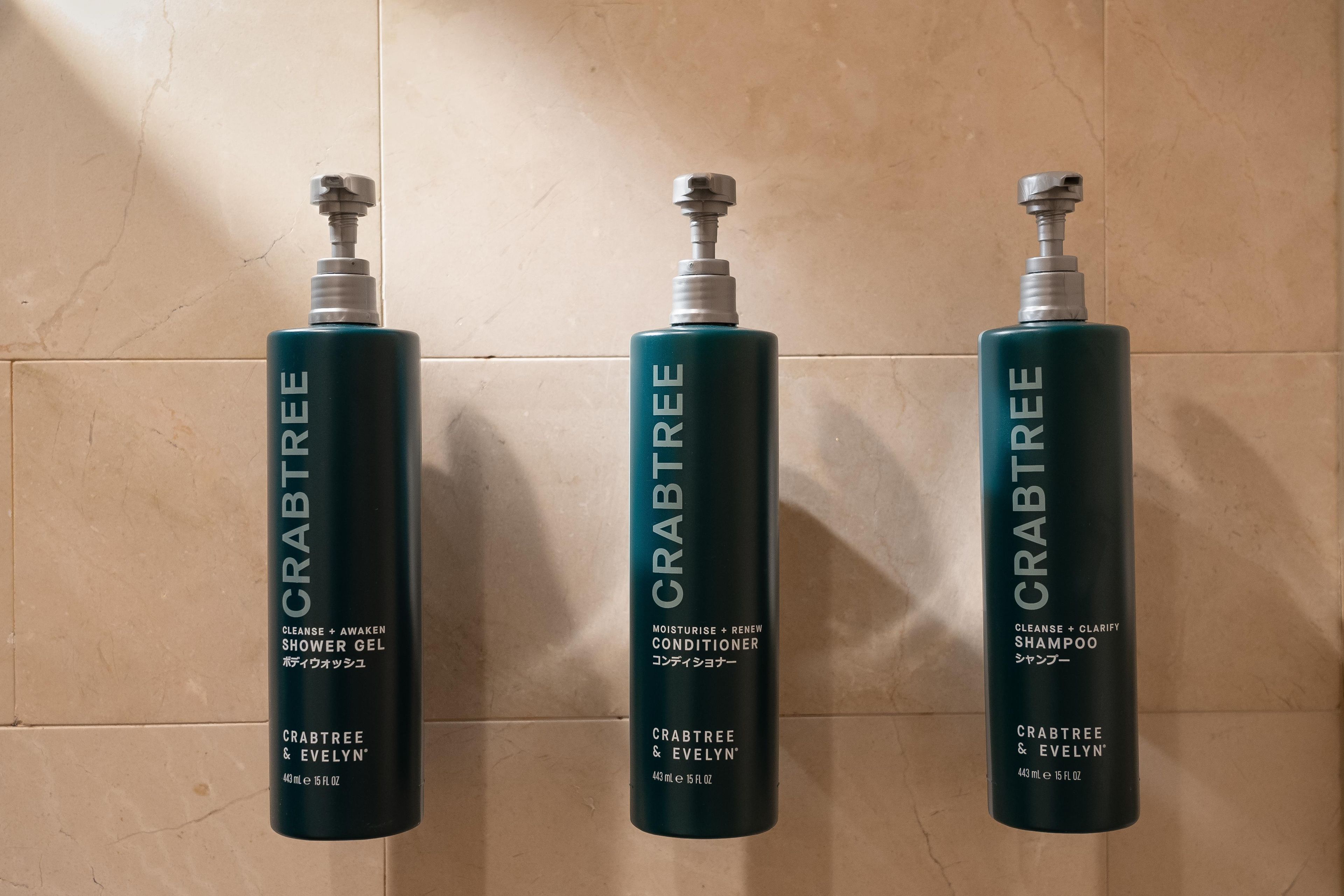 Three bottles of Crabtree & Evelyn products on a tiled wall.
