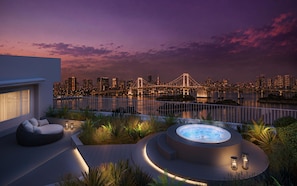 A rooftop terrace with a hot tub, seating area, and a view of a city skyline and bridge at dusk. - Hilton Tokyo Odaiba (Tokyo)