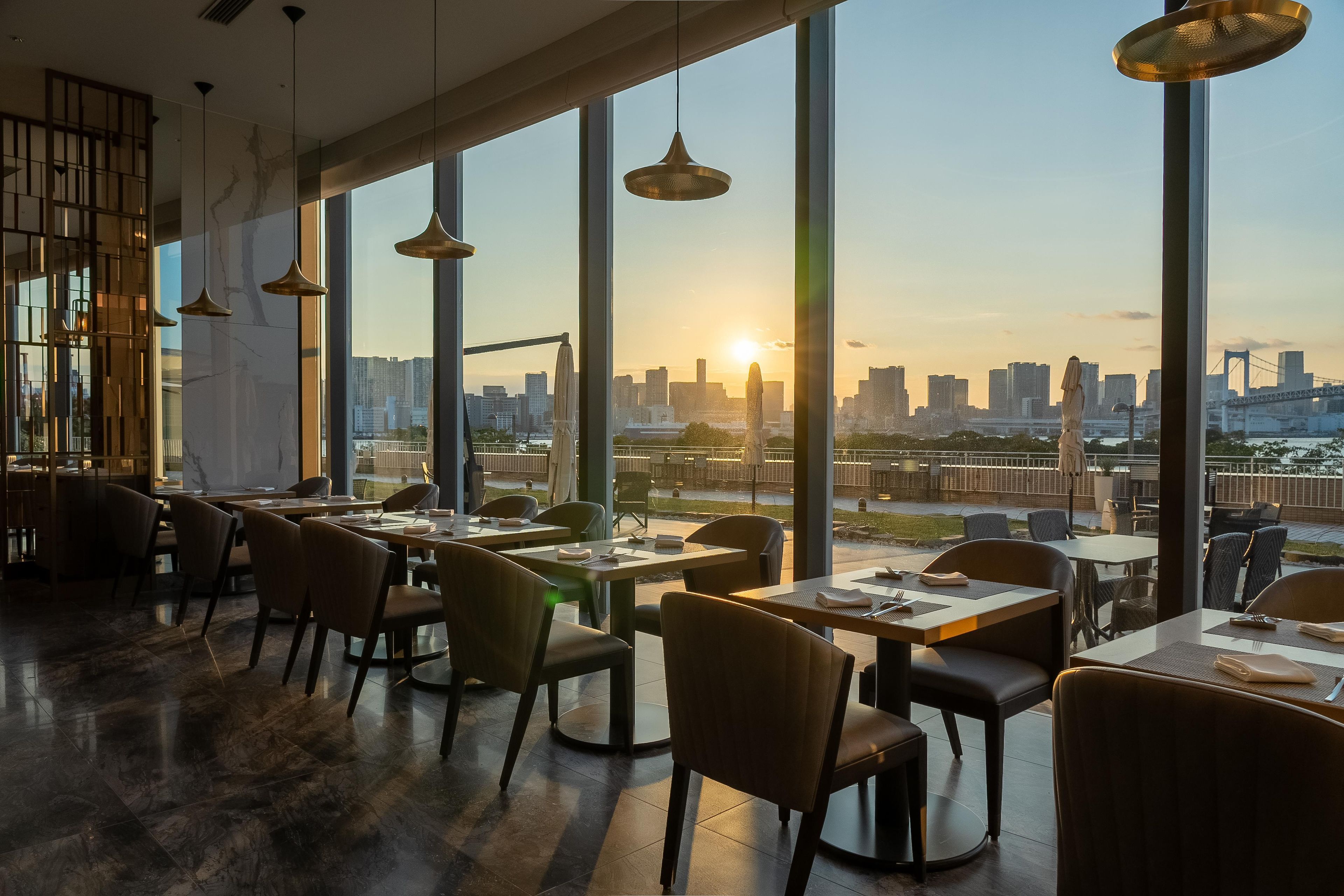 A restaurant with a city skyline view, modern furnishings, and pendant lighting.