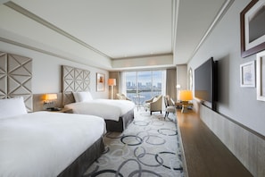 A hotel room with two beds, a city view, a TV, and a small table with chairs.