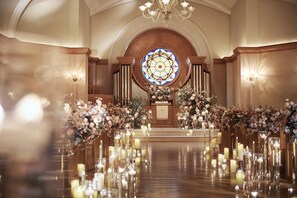 An indoor venue with a central aisle, floral arrangements, and candles. - Hilton Tokyo Odaiba (Tokyo)
