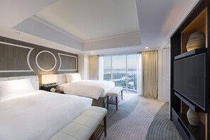A hotel room with two beds, a TV, a large window with a city view, and a modern design.