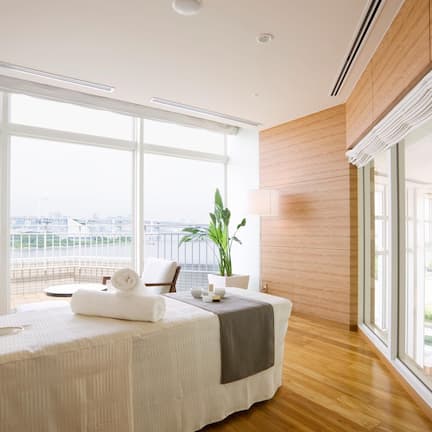 A modern hotel room with a large bed, a sitting area, and a view of the cityscape.