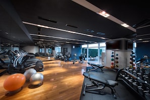 A gym with treadmills, weight machines, and exercise balls.