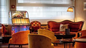 Una habitación acogedora con un jukebox, sillones cómodos, un sofá y una lámpara.