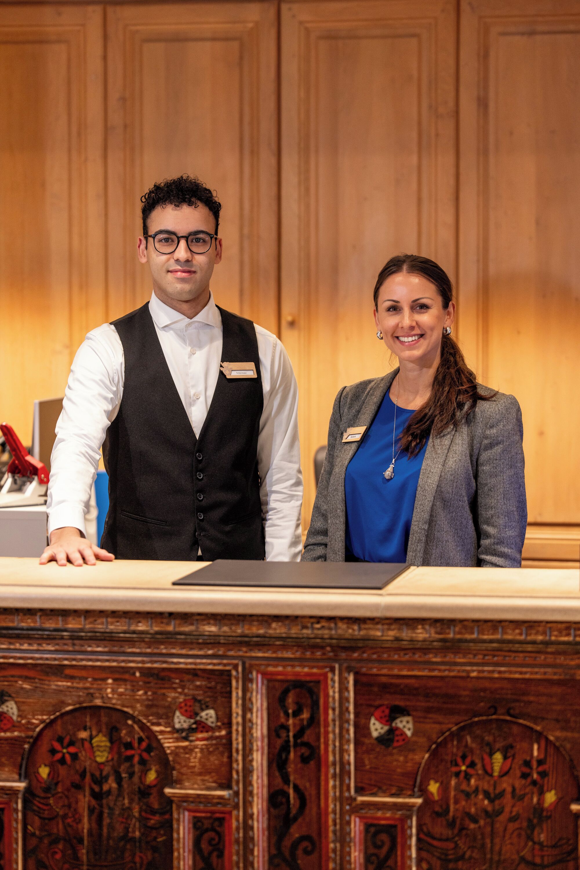A reception desk with a wooden panel background and a name tag holder.