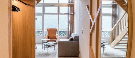 A hallway with a wooden ceiling, a round mirror, a sofa, and a chair.