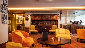 Eine Hotelhalle mit Holzmöbeln, einer Bar und einer Vitrine mit gerahmten Fotos.