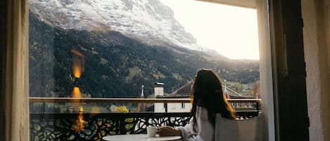 Una persona sentada a una mesa con vista a una montaña nevada.