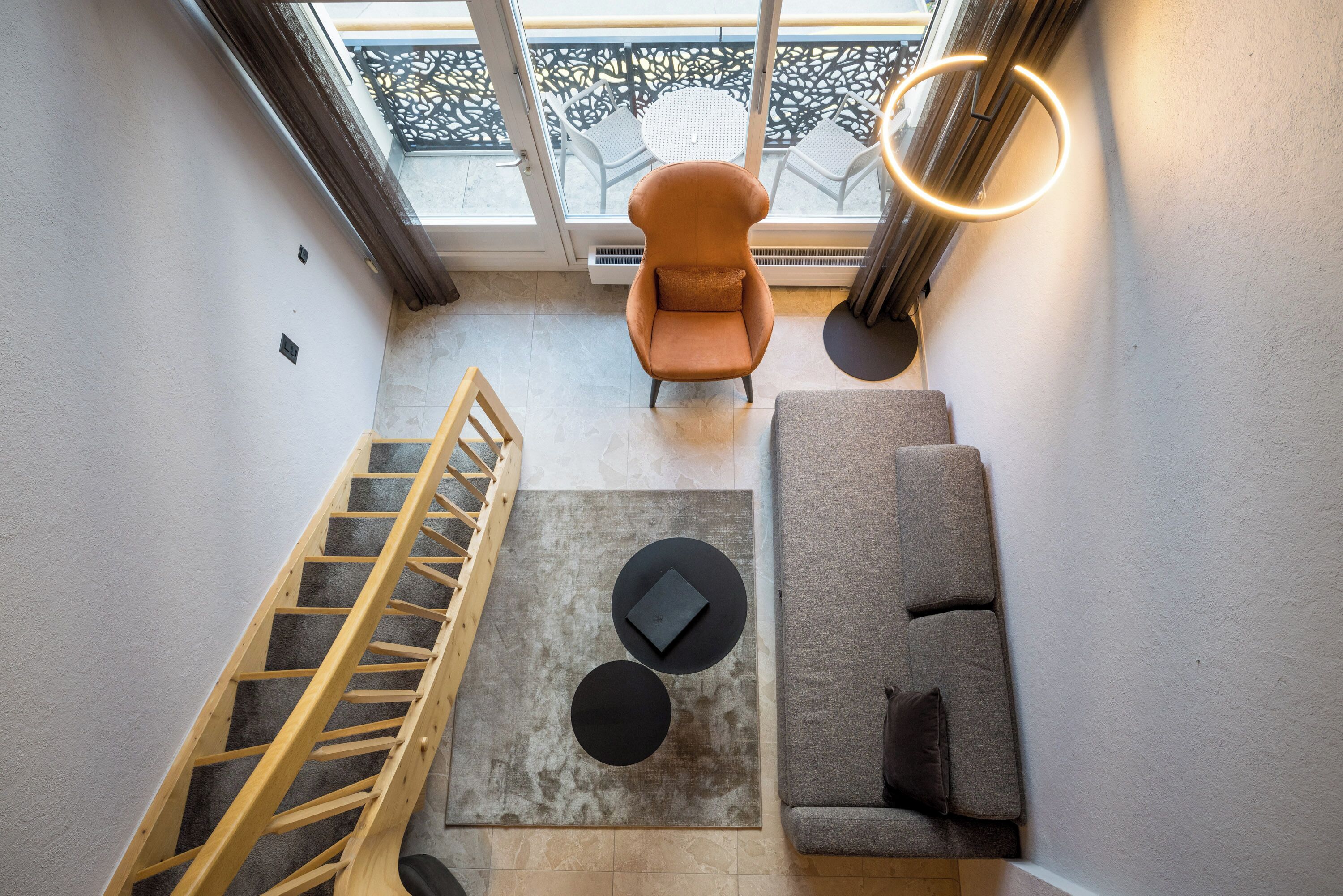 A modern interior with a staircase, a sofa, a chair, and a table.
