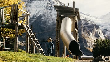 Explore the great outdoors at this mountain playground featuring a slide and climbing area with a ladder.