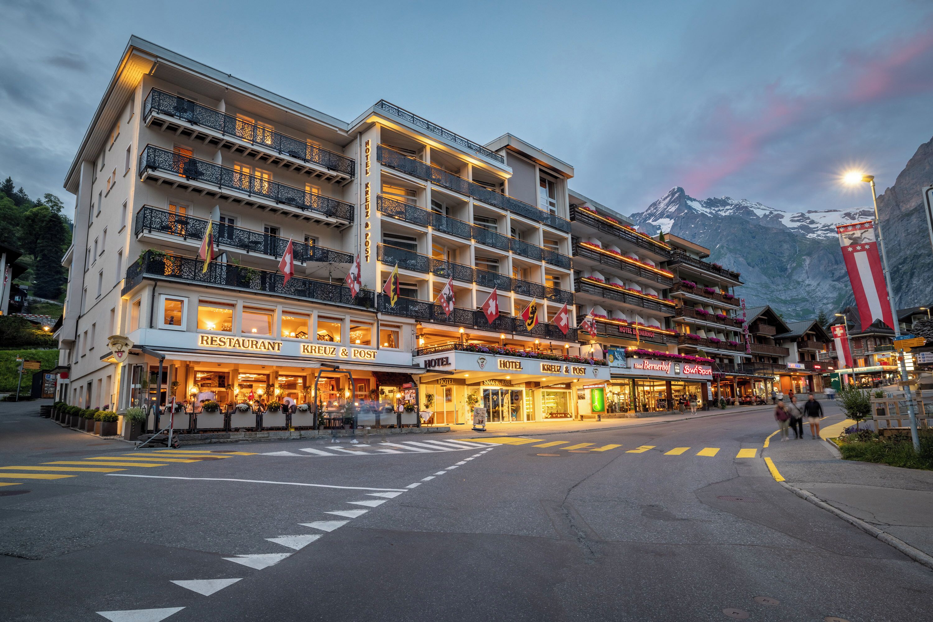 Un hôtel à plusieurs étages doté de balcons, d’un restaurant et de boutiques situées au rez-de-chaussée.