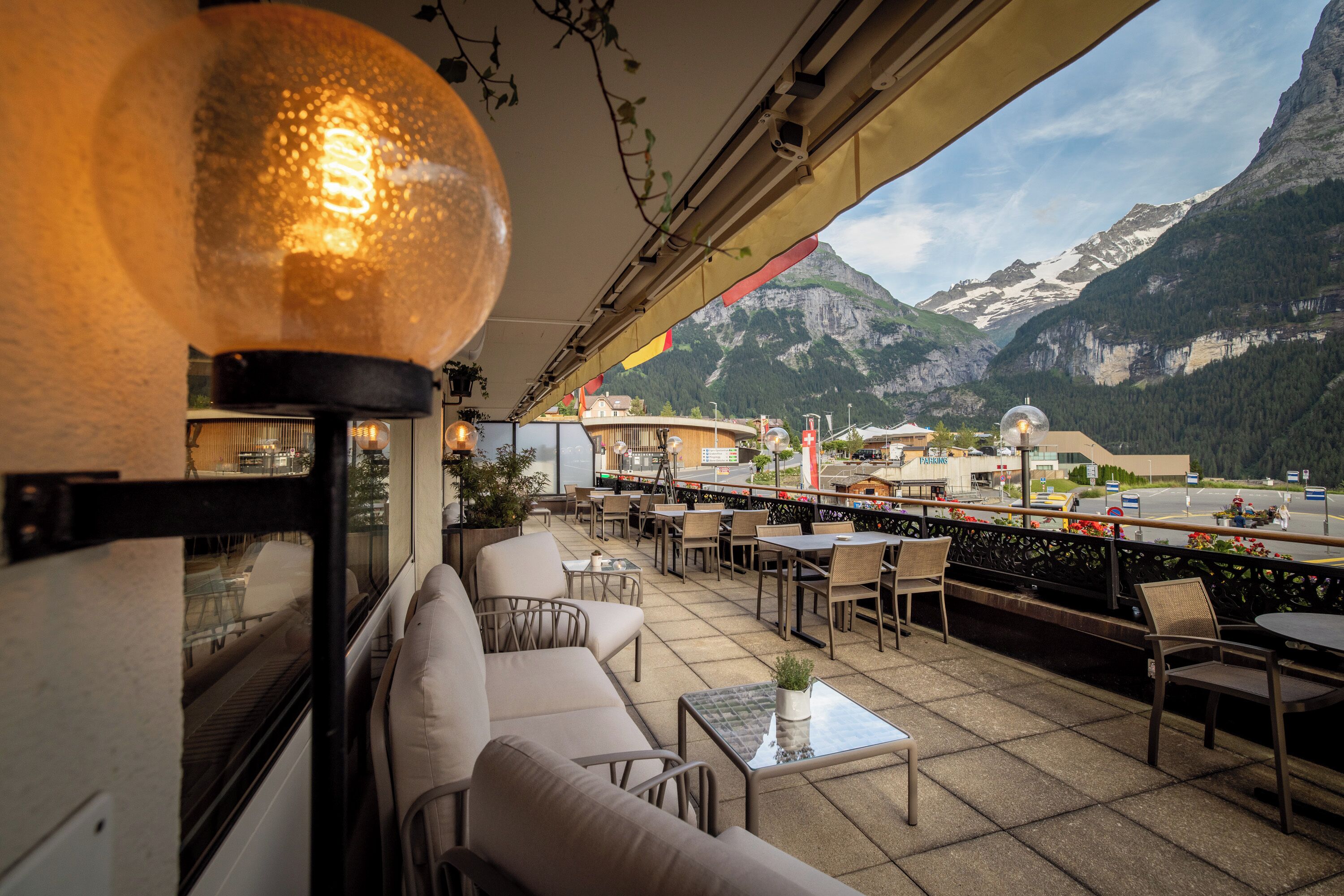 A terrace with outdoor seating, a view of mountains, and a glass table with a plant.