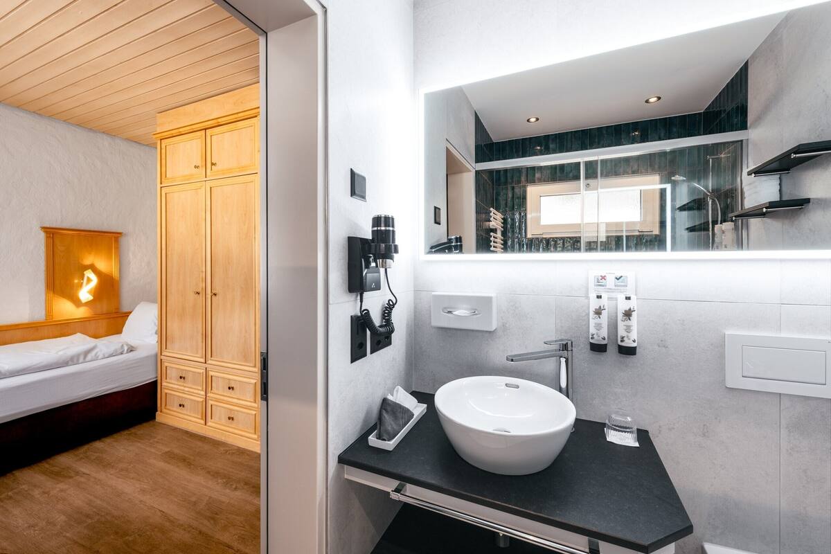 Ein modernes Badezimmer mit einem großen Spiegel, einem weißen Waschbecken und einem Holzschrank.
