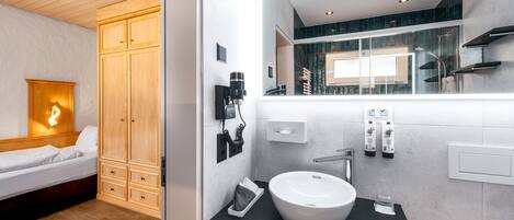 Un baño moderno con un espejo grande, un lavamanos blanco y un armario de madera.