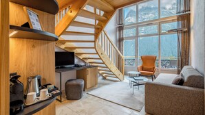 A modern interior with a wooden staircase, a cozy seating area, and a view of mountains through large windows. - Hotel Kreuz & Post (Grindelwald)