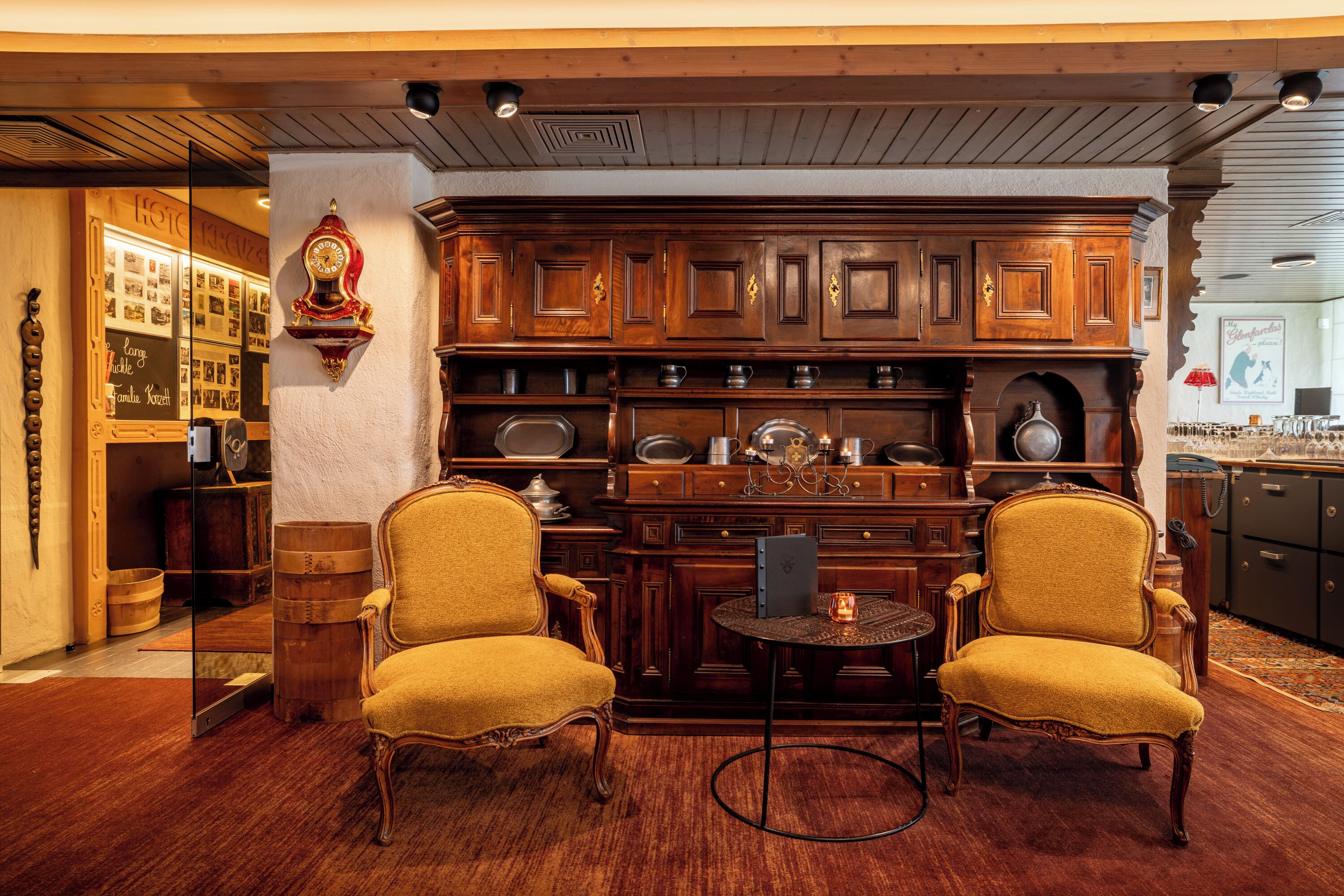 A traditional kitchen with wooden cabinets, two yellow armchairs, and a small round table.