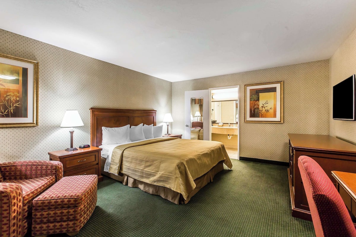 A hotel room with a bed, two bedside tables, a desk, a chair, and a mirror.