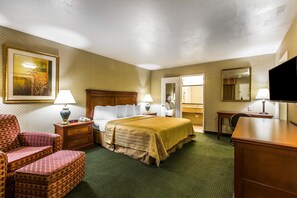 A hotel room with a bed, two bedside tables with lamps, a chair, a desk, a television, and a mirror.
