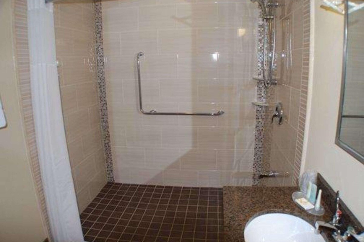 Ducha con barra de apoyo, lavamanos y espejo.