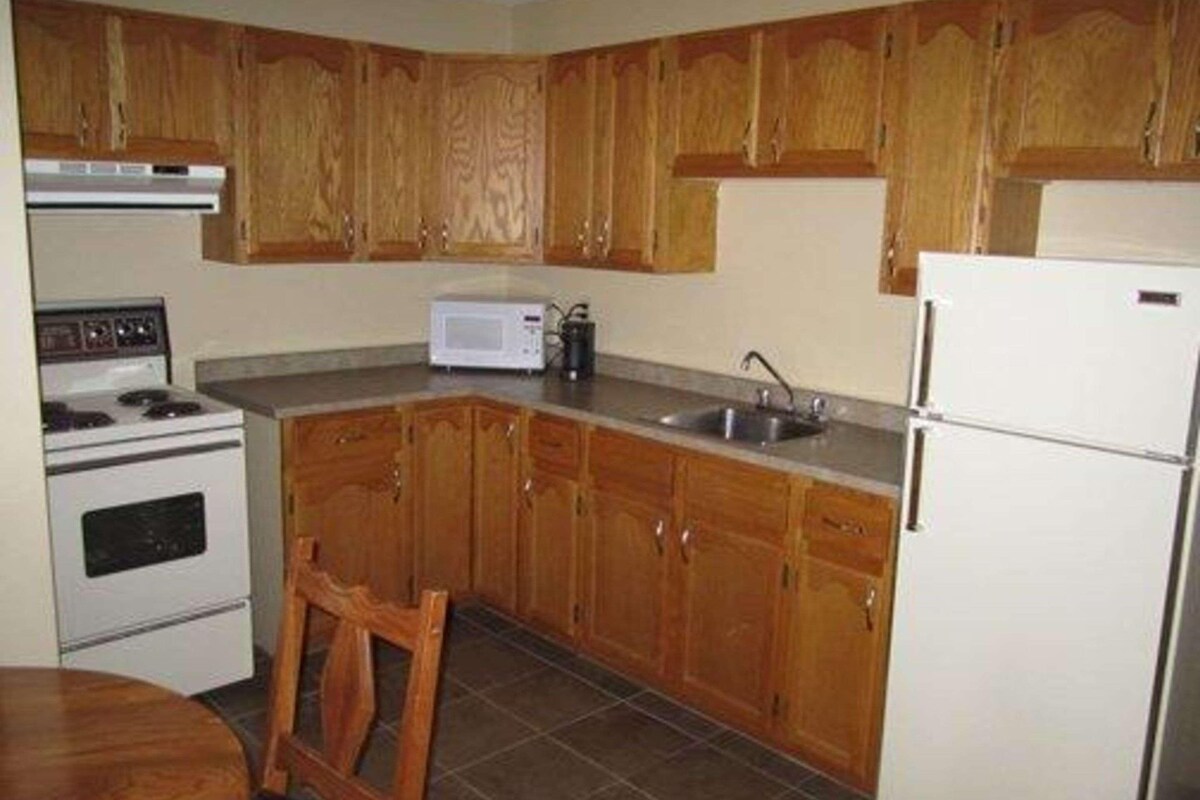 Una cocina con armarios de madera, estufa, microondas, pileta y refrigerador.
