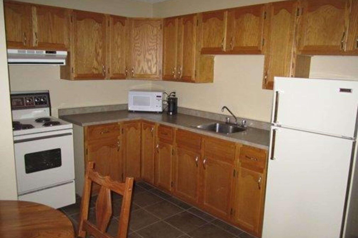 Una cocina con armarios de madera, estufa, microondas, pileta y refrigerador.