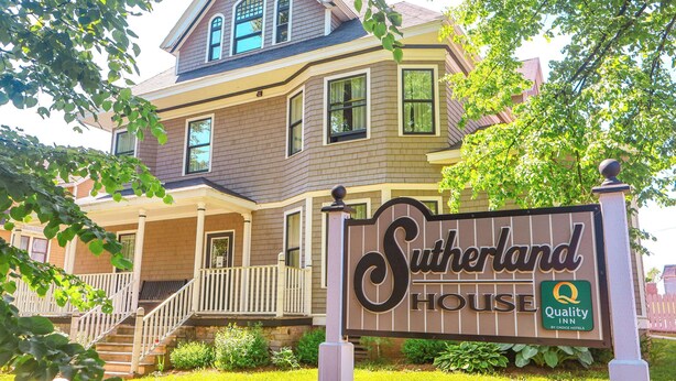 A two-story house with a porch and a sign that reads "Sutherland House Quality Inn by Choice Hotels." - Quality Inn & Suites Downtown (Charlottetown)