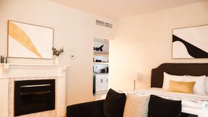A modern hotel room with a fireplace, a large bed with a headboard, and artwork on the walls. - Quality Inn & Suites Downtown (Charlottetown)