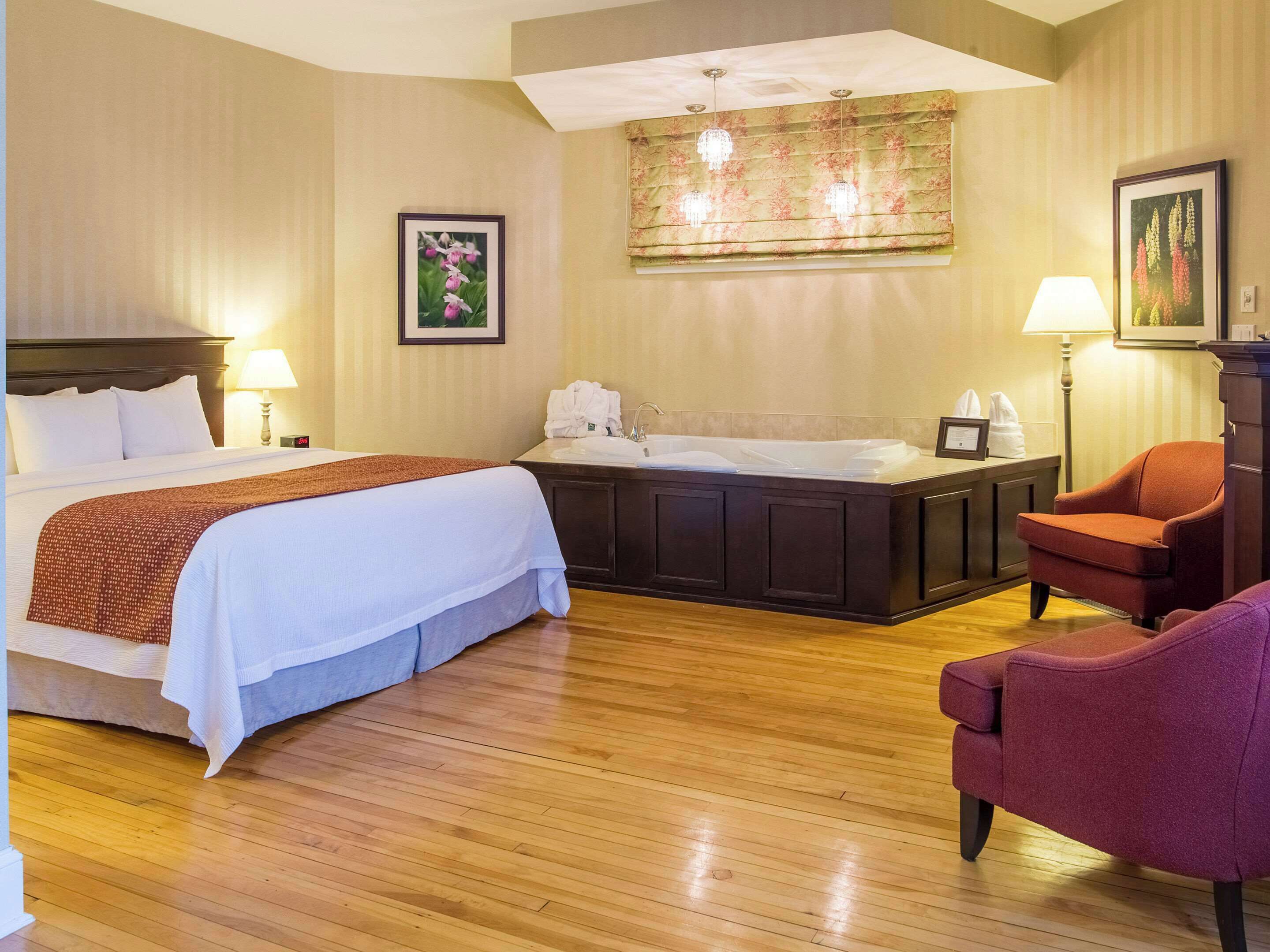 A hotel room with a large bed, a desk with a sink, a chair, and a decorative wall hanging.
