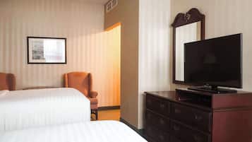 Una habitación de hotel con dos camas, un televisor, un aparador y un cuadro en la pared.