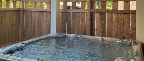 A hot tub with a wooden fence in the background.
