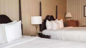 Een hotelkamer met twee bedden, een nachtkastje met een lamp, een telefoon en een stoel.
