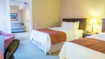 Une chambre d’hôtel avec deux lits, un bureau, une chaise, une table de chevet et une lampe.