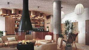 A modern interior with leather sofas, a central black fireplace, wooden shelves, and pendant lighting. - Clubtrotteur Paris, a Tribute Portfolio Hotel (Paris)
