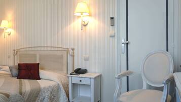 A hotel room with a bed, bedside lamp, nightstand, chair, and a door with a handle.