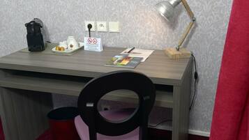 A desk with a coffee maker, a lamp, and a sign indicating no smoking.