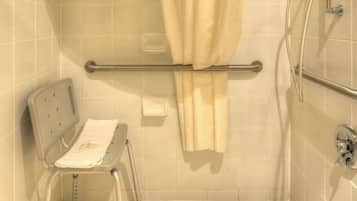 A shower area with a grab bar, a towel rack, and a shower chair.