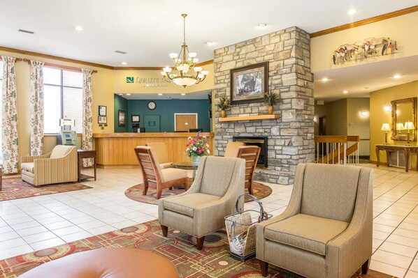 A hotel lobby with a reception desk, a stone fireplace, and comfortable seating areas.