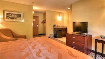 Una habitación de hotel con cama, televisor, cómoda y silla.