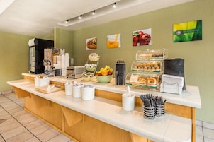 Un mostrador de desayuno con diversos alimentos, máquinas de café y utensilios.