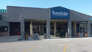 Hotel Travelodge by Wyndham con entrada cubierta, estacionamiento y cielo despejado.