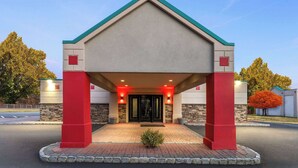 A building with a beige facade, red accents, and a green roof. - Ramada by Wyndham Parsippany (Parsippany)