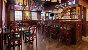 A restaurant interior with wooden tables and chairs, a bar area with a Sapporo beer sign, and various flags hanging from the ceiling. - Ramada by Wyndham Parsippany (Parsippany)