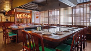 A restaurant with a traditional Japanese interior, featuring wooden tables and chairs, a sushi bar, and sliding doors. - Ramada by Wyndham Parsippany (Parsippany)