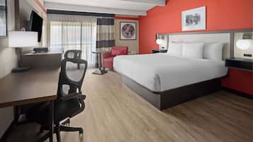 A hotel room with a bed, desk, chair, and a small table.